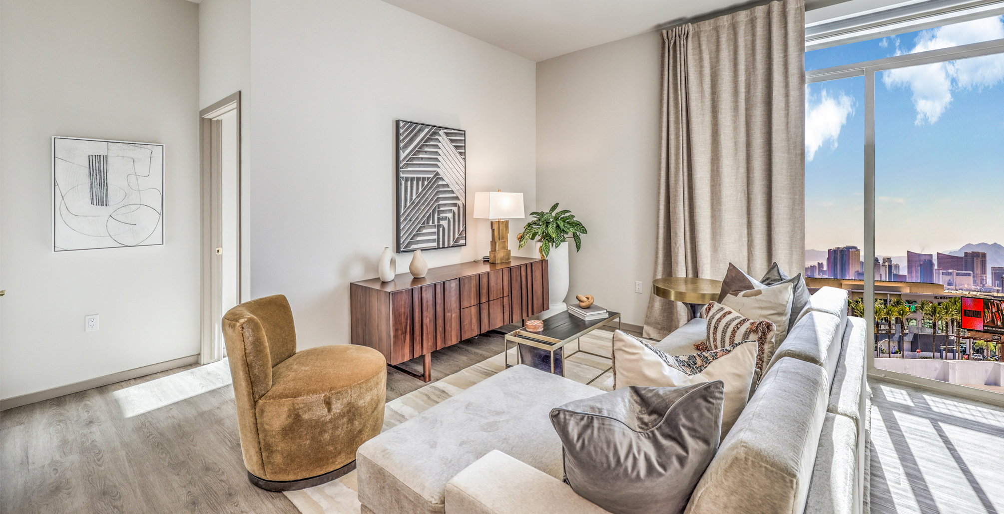 Brand New Apartments in Las Vegas, NV - Vestra at Uncommons - Living Room with Couch, Chair, Window, and Light-Colored Flooring